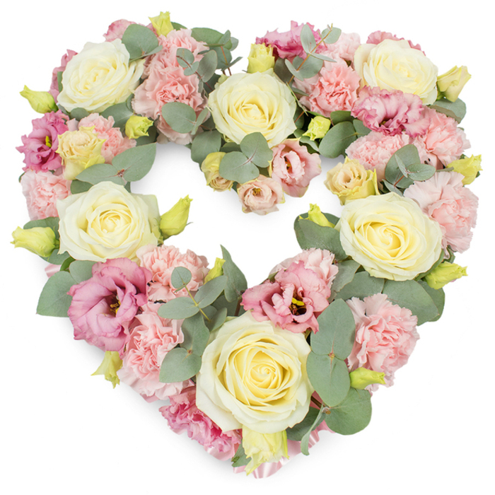 A full, heart-shaped floral tribute is depicted against a stark white background, the flowers arranged in such a way that the heart appears plush, complete, and carefully balanced. Cream and pale yellow roses are placed as the key focal blooms, their velvety petals swirling inward to form elegant, rounded shapes. These roses, evenly spaced across the design, lend structure and a sense of serenity, reminiscent of the calm early mornings along Leyton High Road before the day begins. The spaces between the roses are generously filled with light pink carnations, their many frilled petals overlapping to create a soft, textured surface that adds tenderness and volume to the heart. Interspersed among these are more intensely coloured flowers: deeper pink and mauve lisianthus with gently flared petals and occasional darker centres, drawing the eye in and adding depth, like shaded areas beneath mature trees in nearby local parks. Sprinkled throughout are small, yellow-green buds, quietly hinting at youth, new life, and the freshness of a recently created arrangement. Woven delicately among the blooms, silvery-green eucalyptus leaves curve around and through the heart, their smooth, rounded shapes and muted tones bringing a cool, calming balance to the pastel palette. The flowers are tightly packed, creating a luxurious, cushion-like effect with no gaps, ensuring the heart shape remains clear and expressive from every angle. This arrangement is ideal as a funeral wreath, memorial tribute, or expression of condolence in Leyton and the surrounding neighbourhoods, symbolising enduring love, cherished memories, and the gentle support of community. The combination of roses, carnations, lisianthus, and eucalyptus reflects the touch of a skilled local florist, attuned to both the emotional weight of farewell and the quiet comfort that beautiful flowers can bring.