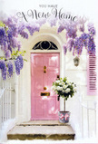 This doorway tableau could easily belong to a quiet corner of Leyton, maybe tucked along a side street off Francis Road, where a new homeowner has just received a heartfelt floral delivery. The front door is painted a gentle, dusty pink, the sort of comforting shade that catches the afternoon light and softens it, turning it warm and inviting. Above and around the door, wisteria pours down in voluptuous trails of lavender blossoms. The clusters hang like soft garlands, each made of tiny lilac petals that together form a loose, cascading veil against the whitewashed wall. The wall itself is simple and bright, its fine texture catching hints of sunlight and faint shadow so that the entire façade feels alive but serene. On the stone doorstep, a grey tin bucket rests solidly, placed at a slight angle that suggests it has just been set down by a careful hand. Inside, a lush bouquet of white and cream roses fills the bucket to overflowing. The roses are fully open and velvety, with layered petals that gently curve and fold, creating a plush, cloud-like effect. Soft green foliage is threaded through the arrangement, offering contrasts of shape and colour that keep the display natural and relaxed, in tune with Leyton's unpretentious character. Around the base of the bucket is tied a supple satin ribbon in pale pink, its bow loose and graceful, echoing the shades of both door and wisteria. The mood is gently celebratory and very personal, ideal for sending congratulations on a new Leyton home, and for making the simple act of stepping over the threshold feel wrapped in beauty, comfort, and the promise of many happy days ahead.